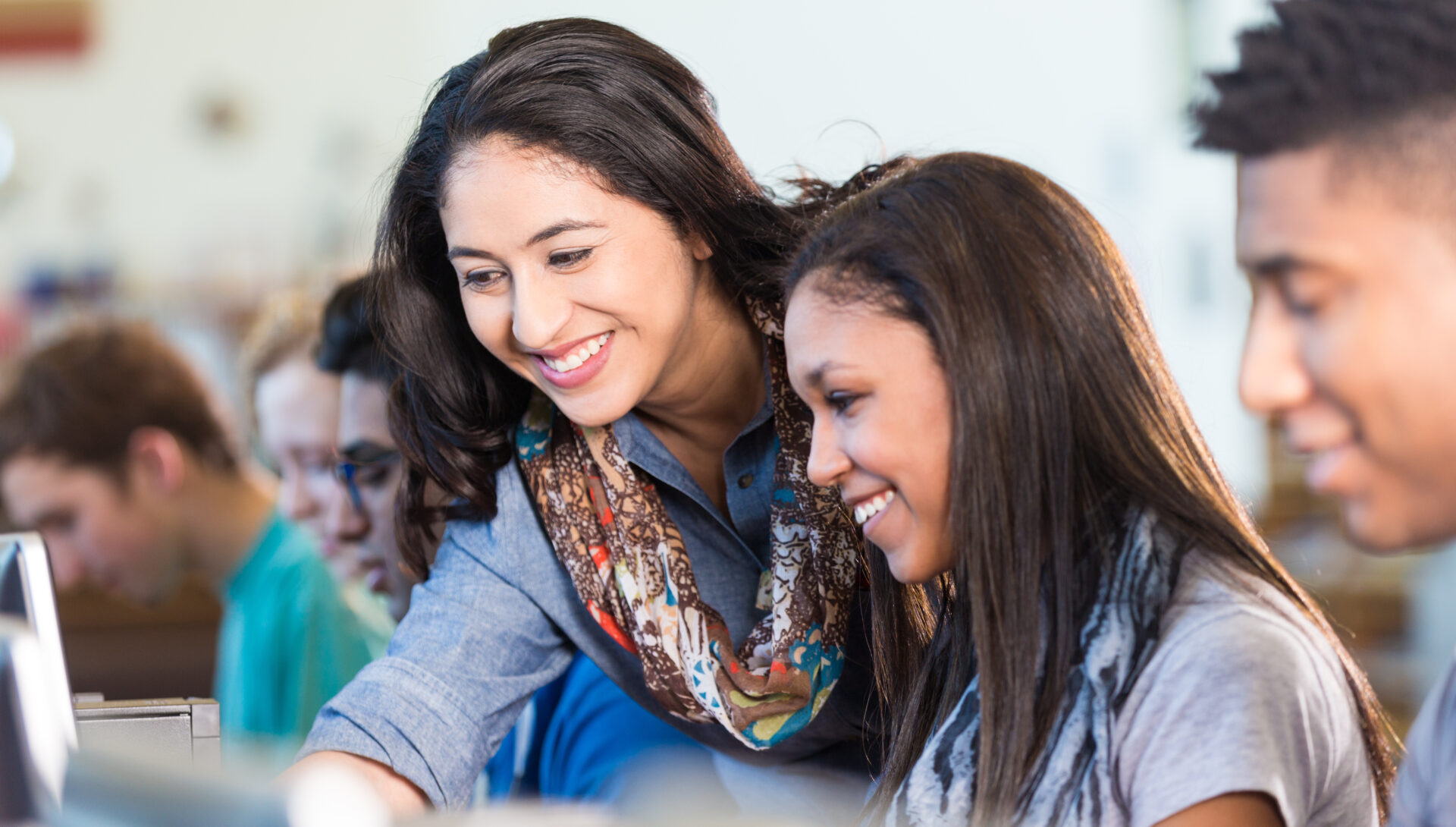 Friendly teacher assisting Hispanic high school student with library ...