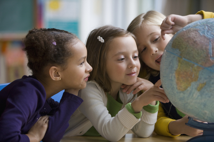 Students looking at a globe in the classroom. 
