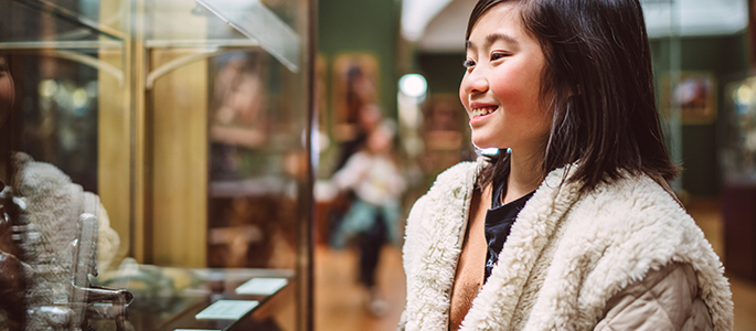 A teenage girl looks at an exhibit in a museum - Cambridge Primary and Lower Secondary Humanities and Global Perspectives