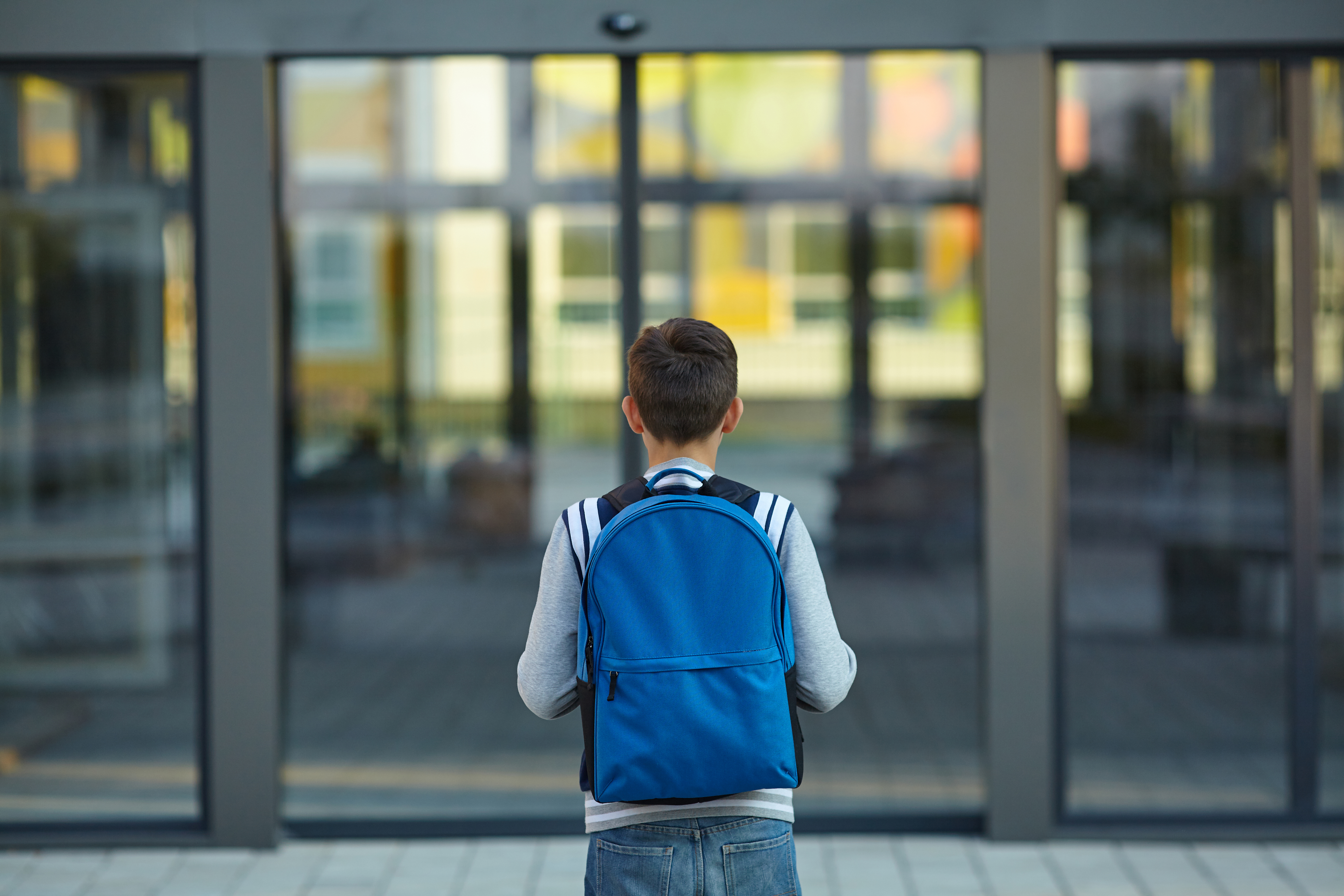 Boy stands in front of school doors