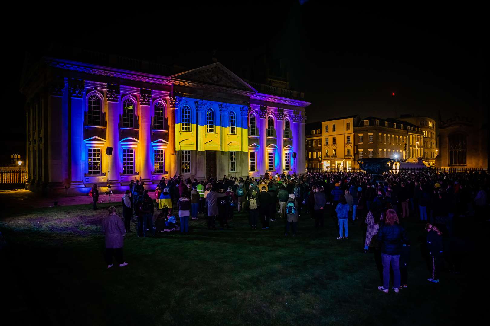 Senate House at Cambridge lit up in blue and yellow lights