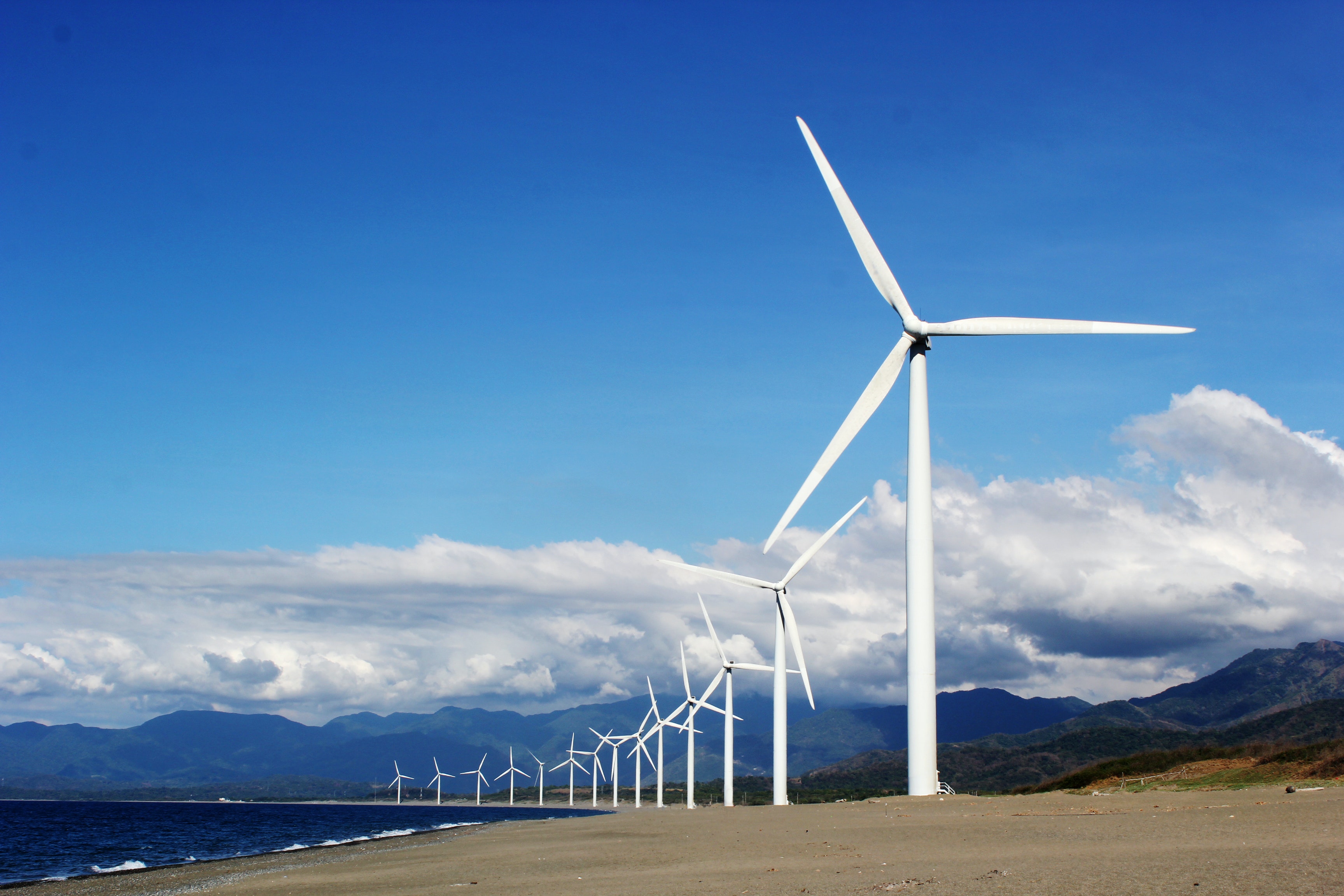 a line of wind turbines set against a blue sky