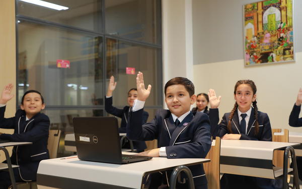 Students in a classroom with their hands raised up