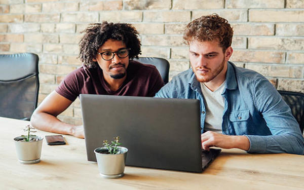 Two adult students working at a laptop together 