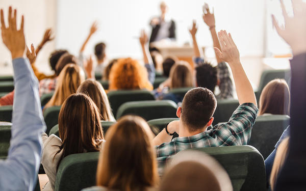 Students in classroom raising their hands