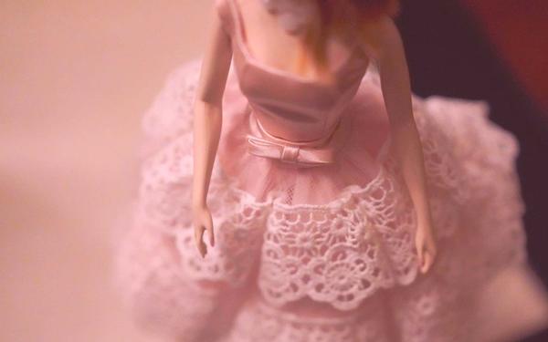 Close up of a toy doll in pink dress.