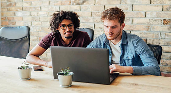 Two adult students working at a laptop together 