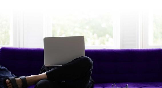 Person working on laptop sat on sofa at home