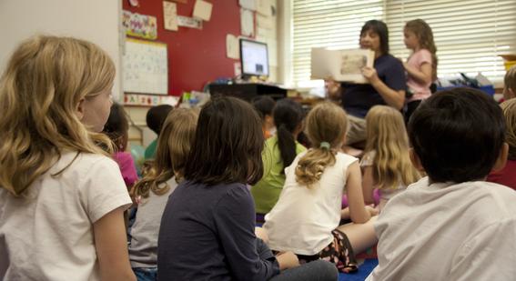 a teacher reading a book to a class of children