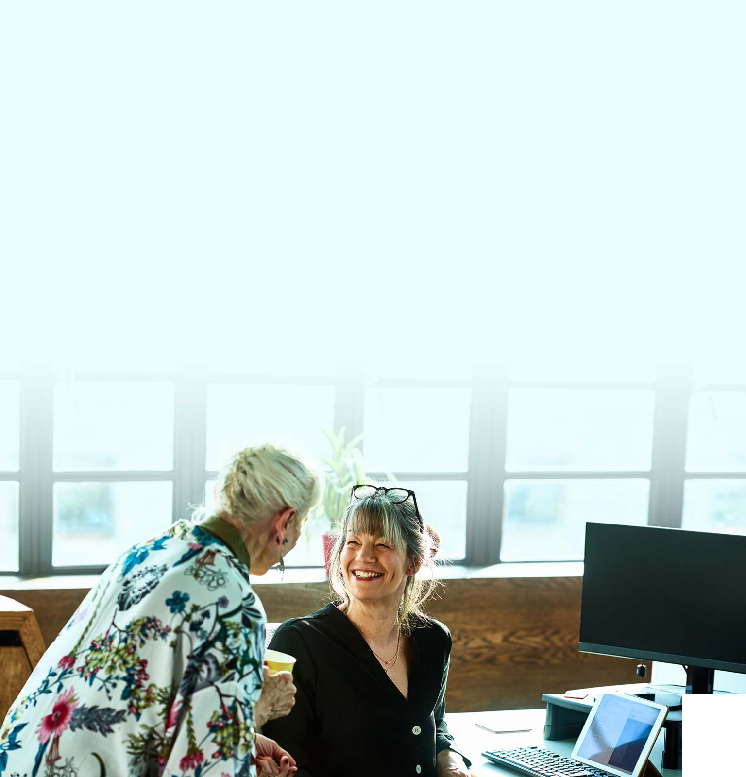 woman sat at desk smiling up at a colleague