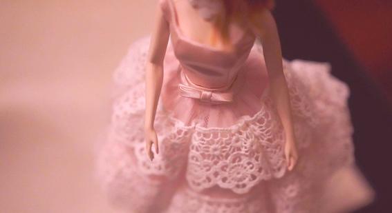 Close up of a toy doll in pink dress.